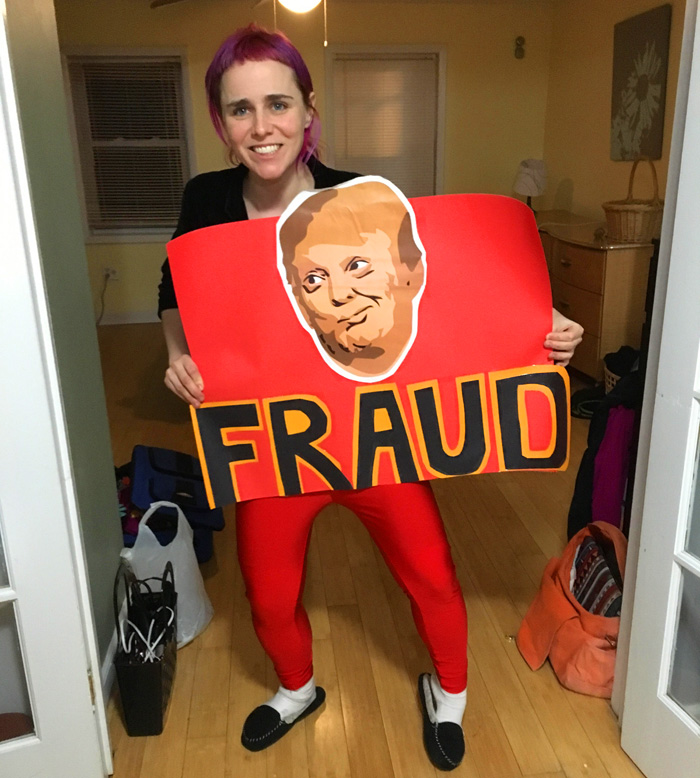 erica holding a sign with the face of Trmp and the word FRAUD