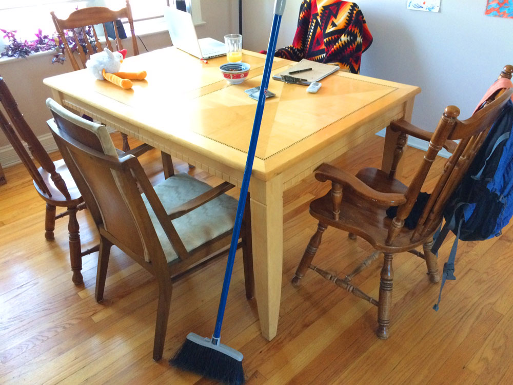 broom leaning against a kitchen table