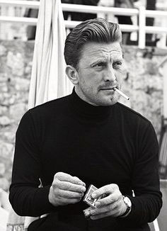 black and white photo of young Kirk Douglas smoking a cigarette and wearing a dope black turtleneck